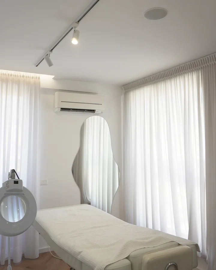 Treatment room at Nouvelle Clinique Tirana with medical bed and magnifying lamp